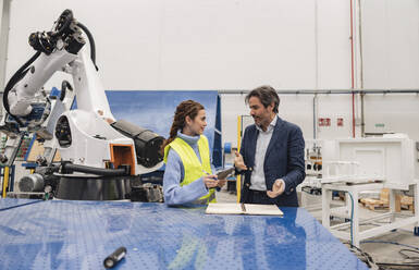 Engineers having discussions standing in robotics factory - JCCMF09723