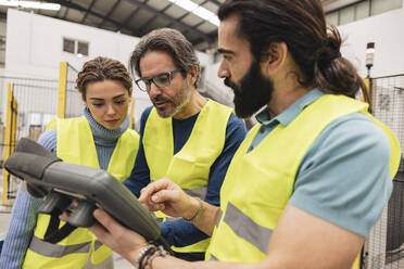 Engineers using controller in robotics factory - JCCMF09757