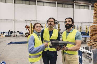 Ingenieure halten das Bedienfeld in der Roboterfabrik und schauen nach oben - JCCMF09761