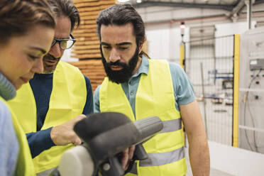 Engineer with colleagues using control panel in factory - JCCMF09765