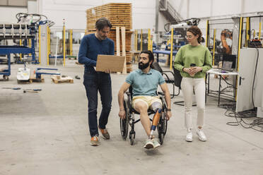 Ingenieur im Rollstuhl sitzend mit Kollegen in der Robotikfabrik - JCCMF09787