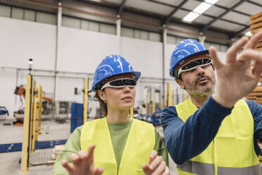 Älterer Ingenieur mit einem Kollegen, der in einer Fabrik gestikuliert - JCCMF09822