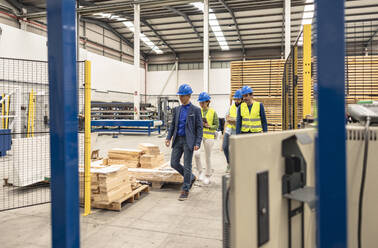 Engineers wearing hardhats walking in factory - JCCMF09836