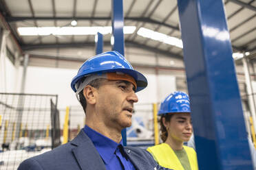 Ingenieur und Kollege tragen Schutzhelme in einer Fabrik - JCCMF09839