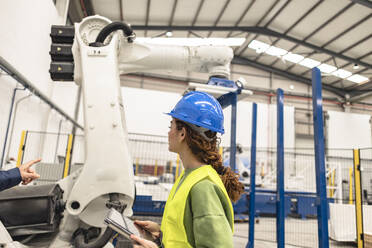 Ingenieur erklärt Kollege über Roboterarm in Fabrik - JCCMF09840