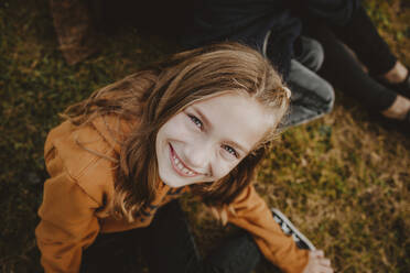 Happy girl with brown hair sitting in park - MDOF00855