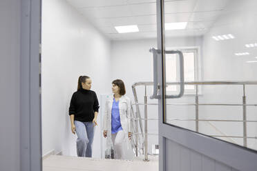 Arzt und Patient beim Treppensteigen im Krankenhaus - SANF00084