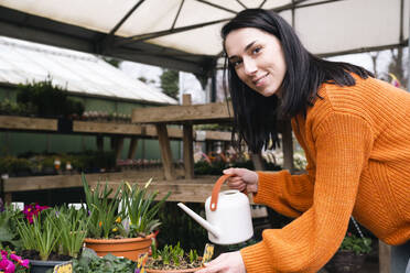 Smiling woman with watering can in garden center - AMWF01219