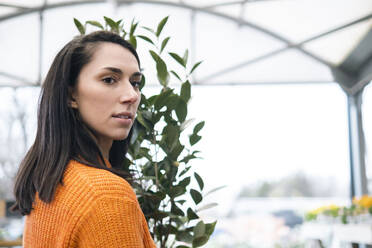 Young woman with plant in nursery - AMWF01235