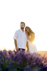 Von hinten beleuchteter Mann und Frau in einem Lavendelfeld stehend - JJF00385