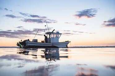 Floating boat with unrecognizable fisherman in rippling seawater - a  Royalty Free Stock Photo from Photocase