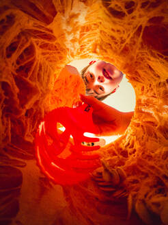 Boy carving a jack-o-lantern shot up through bottom of pumpkin. - CAVF96674
