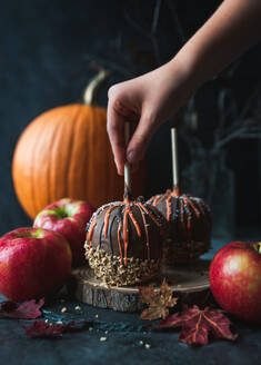 Hand reaching for chocolate caramel candy apple for Hallowe'en. - CAVF96677