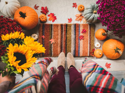 Top view of woman standing in doorway surrounded by fall decor. - CAVF96678