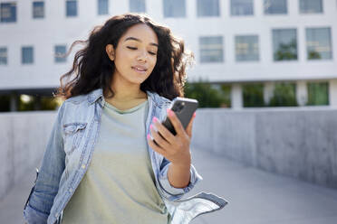 Frau mit langen Haaren schaut auf ein Mobiltelefon - CAVF96692