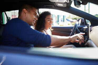 Lächelndes Paar benutzt GPS, während es in einem Elektroauto sitzt - CAVF96701