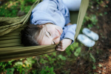 Teen girl laying in hammock smiling - CAVF96734
