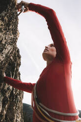 Eine Frau in einem roten Hemd klettert an einem sonnigen Tag. - CAVF96735