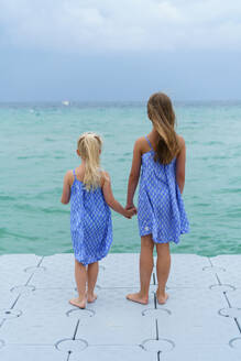 Zwei Schwestern schauen auf das blaue Meer. - CAVF96744