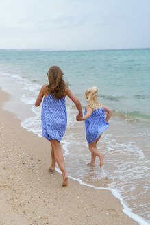 Two sisters running at the beach. - CAVF96745