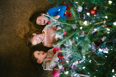 Geschwister lachen und lächeln unter der Weihnachtsbaumbeleuchtung - CAVF96766
