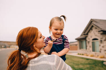 Playful mom holding baby outside holding house keys - CAVF96772