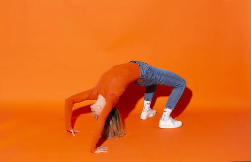 Frau macht Brücke Position gegen orange Hintergrund - MIKF00147