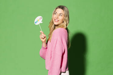 Lächelnde Frau hält Sprechblase mit Hurra-Text auf grünem Hintergrund - MIKF00149