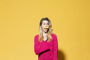 Frau mit falschem Schnurrbart vor gelbem Hintergrund - MIKF00173