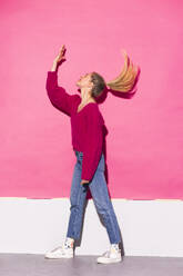 Woman gesturing over face standing against pink background - MIKF00195