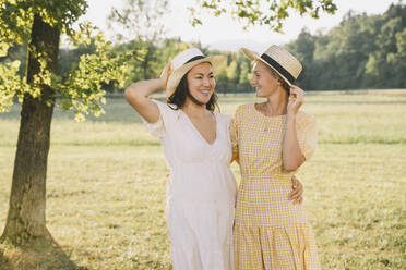 Glückliche Frauen mit Hüten stehen im Park - NDEF00386