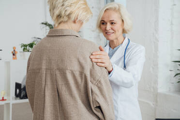 Smiling doctor consoling patient at clinic - VPIF07980