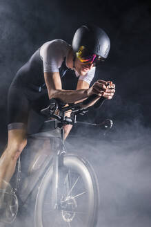 Radfahrer übt Radfahren auf dem Turbotrainer inmitten von Rauch - STSF03704