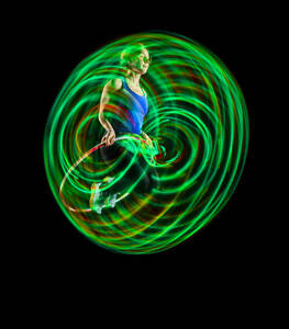 Woman doing exercise with hula hoops against black background - STSF03705