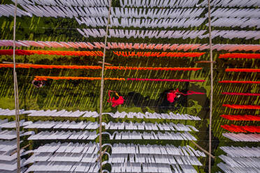 Aerial view of people working in an open air laundry with colourful fabric hanged to dry in Narayanganj, Bangladesh. - AAEF17340