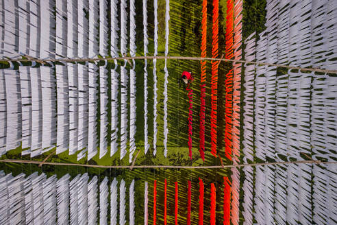 Aerial view of people working in an open air laundry with colourful fabric hanged to dry in Narayanganj, Bangladesh. - AAEF17341