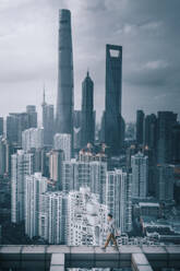 Luftaufnahme einer Person, die auf einem Dach spazieren geht, mit der Skyline von Shanghai im Hintergrund, China. - AAEF17462