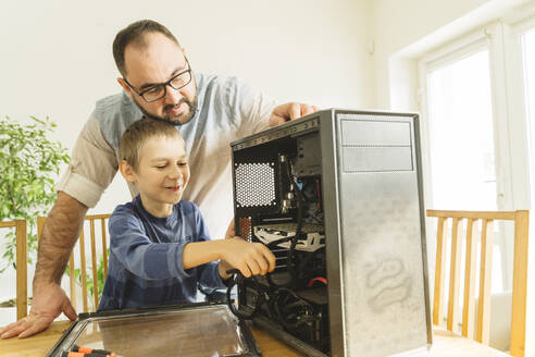 Vater stehend mit Sohn bei der Reparatur eines Computers zu Hause - OSF01437