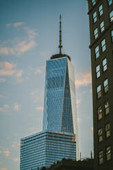 Contemporary high skyscraper with mirrored windows located against blue cloudy sky during sunset in city district of New York - ADSF43249