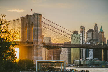 Herrliche Aussicht auf die berühmte Brooklyn Bridge in New York City gegen den Sonnenuntergang Himmel über dem Fluss - ADSF43261