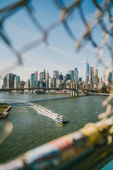 Blick durch den Metallzaun der Brooklyn Bridge über den East River in der Nähe von Wolkenkratzern in New York USA - ADSF43266