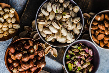 From above bowls with different kinds of nuts on concrete table background - ADSF43273