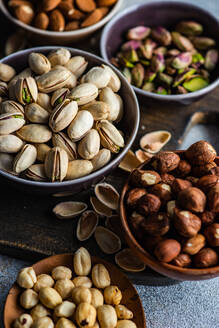 From above bowls with different kinds of nuts on concrete table background - ADSF43274