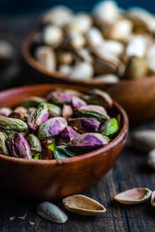 Raw organic pistachio nuts in the bowl on dark background - ADSF43276