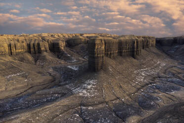 Szenische Drohnenansicht eines vulkanischen Geländes mit Sandsteinklippen verschiedener Formen gegen einen bewölkten Sonnenuntergangshimmel in Hanksille, Utah, USA - ADSF43420
