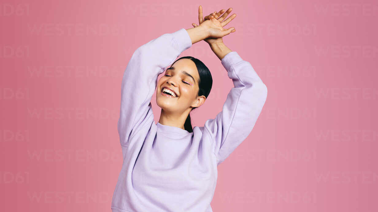 Middle aged woman in trendy pink clothing smiling at you, studio