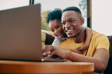 Ein Vater spielt seiner Tochter einen Kinderfilm auf einem Laptop vor. Ein Vater in den 30ern erzieht seine Tochter im Vorschulalter mit Hilfe moderner Technologie. Vater und Tochter verbringen einige Zeit zu Hause. - JLPSF29542