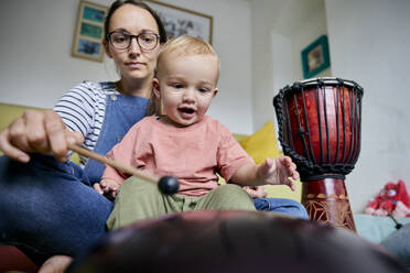Mutter und Kleinkind spielen zusammen ein Musikinstrument im Haus - MINF16616
