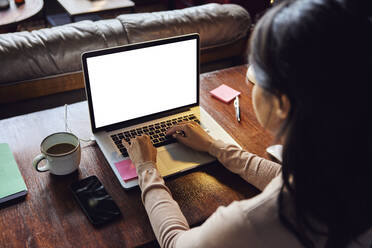 Businesswoman working on laptop at desk in loft office - BSZF02265