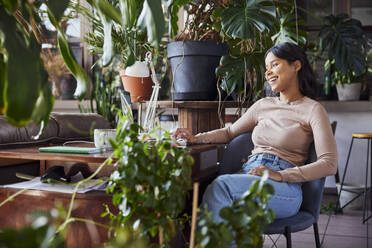 Happy freelancer using laptop sitting at desk in loft office - BSZF02267